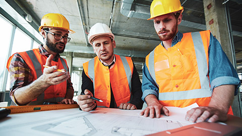 Three construction supervisors discussing the priorities of a project