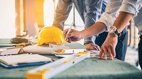 Coworkers looking over plans on a workbench