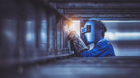 Construction worker welding wearing appropriate personal protective equipment