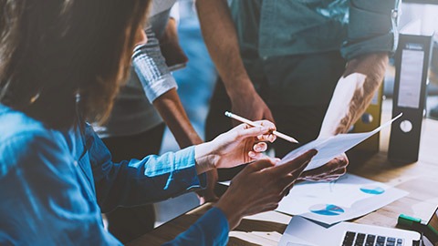 A tight shot of a group of business people examining a construction document that they are about to sign