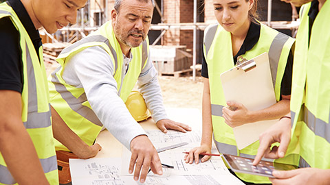 Construction manager explaining building process to his three apprentices