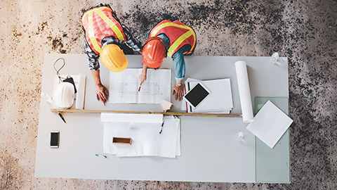 Top down view of construction workers looking at plans on a table