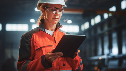 A mid-shot of a construction worker checking job-related information on a tablet device