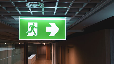 An emergency exit sign and emergency lighting in the interior of a modern office