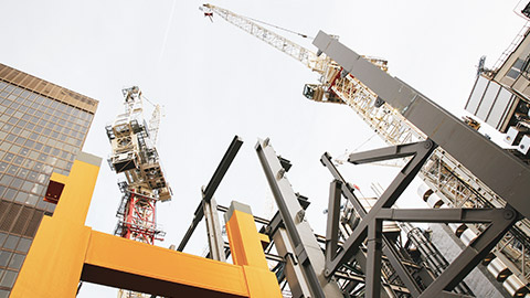 A view looking up at a construction site with cranes