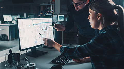 A pair of engineers looking at a drawing on a computer screen