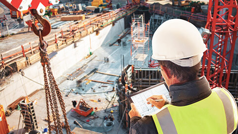 Over the shoulder view of a foreman looking over plans on a building site