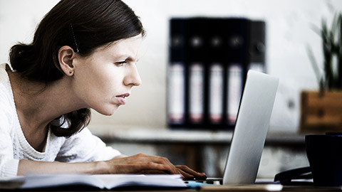 A person squinting while reading on a laptop