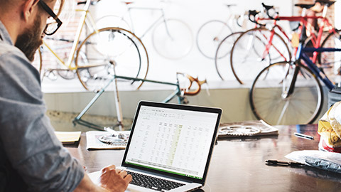 A small business owner working on a spreadsheet on a laptop