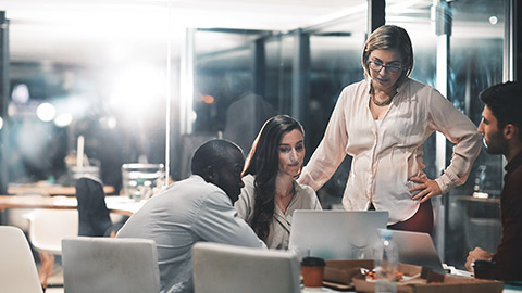 A group of accountants in a room looking at a laptop