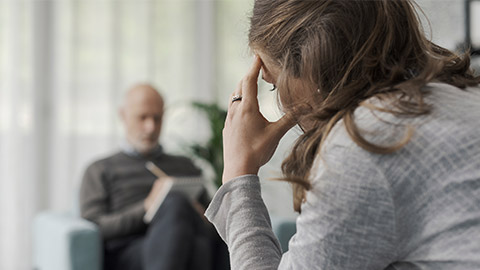 Professional therapist writing notes while listening to his patient during a psychotherapy session