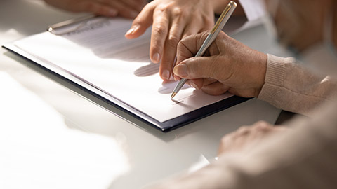 Close up of aged woman hand signing contract