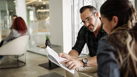 Mature businessman going over a paperwork with a colleague while sitting together in the lounge area