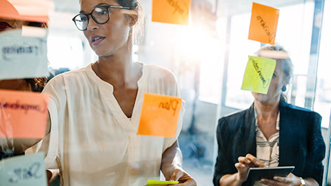 2 work colleagues writing on sticky notes