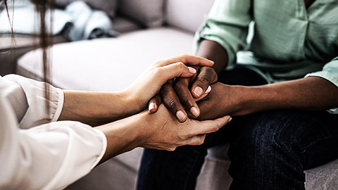 A counselling holding a clients hands