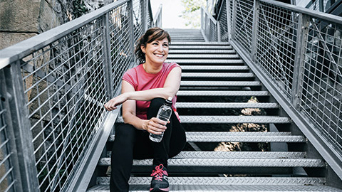 happy woman sitting on metallic stair outdoor