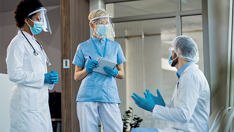 Two doctors and nurse communicating in a hallway while working in the hospital