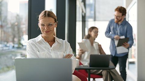 Female sales manager working on laptop sitting in modern coworking on colleagues background