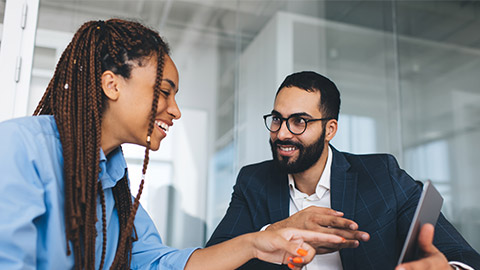 Cheerful multiracial colleagues discussing startup project and smiling during workday in office