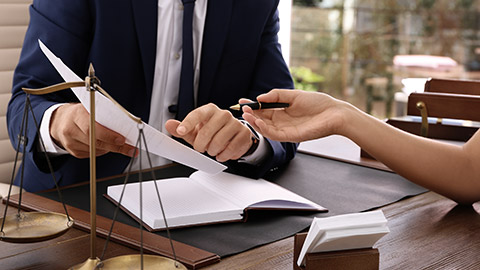 Lawyer working with client at table in office, focus on hands