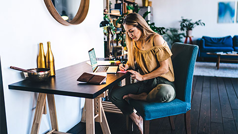 A young professional seated at their desk, writing down key objectives of their business