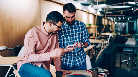 2 designers checking an app on a mobile phone