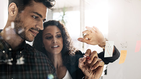 Two people developing and planning on glass board