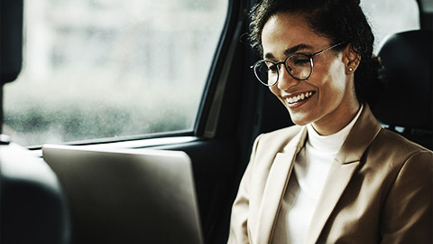 A business person with laptop in back seat of car