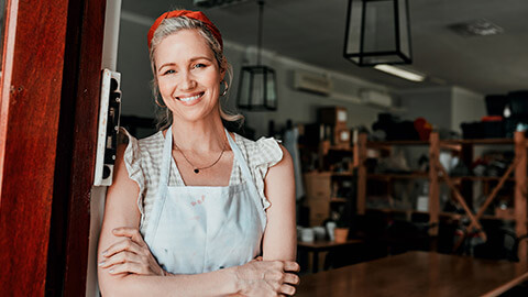 A small business owner standing at the doorway of their business