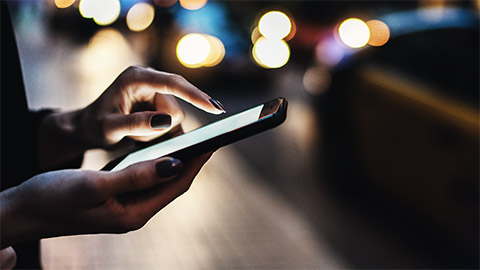 A persons hand using a smartphone in a train station