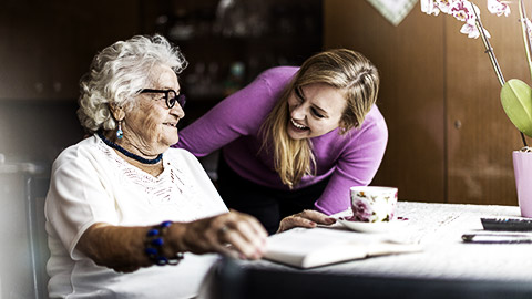 A carer happily spending time with an elderly