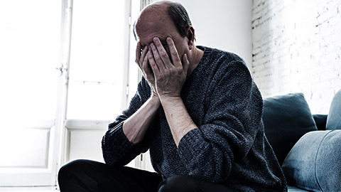 An elderly person frustrated hand over face