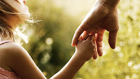 A child holding onto an auldts hand