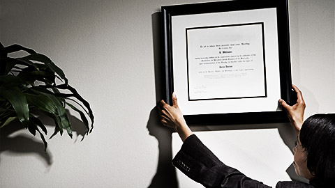 A person putting up a certificate on a wall