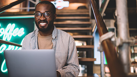 A young business professional smiling at the camera in a modern office environment