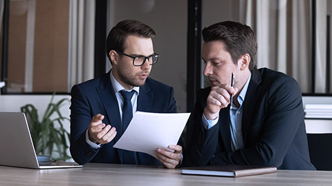 serious supervisor analyzes the paper with coworker