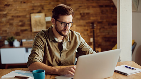 Freelance worker using laptop and typing an e-mail while working at home