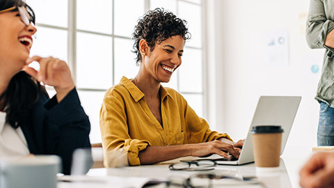 Black business woman using a laptop in a meeting with her team