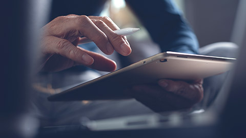 A close view of a person writing notes on a tablet device