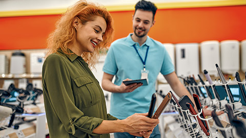 girl is talking to a male salesperson while getting help buying a new hair straightener at a hardware and electronics store