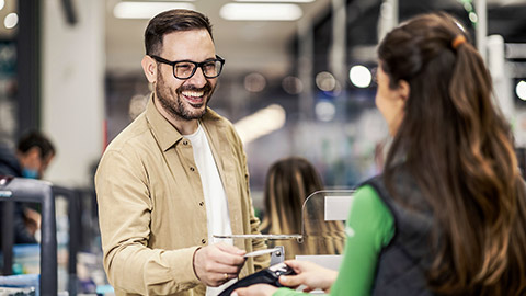 A smiling customer using credit card in supermarket at checkout