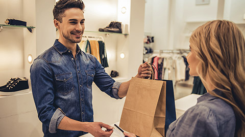 shop assistant is smiling while giving purchases and credit card to beautiful client