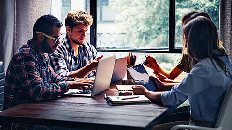 A small team holding a casual meeting at a table by a window