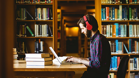 A person studying in a library alongside shelves of books