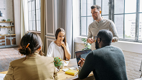 team of young and successful employees listen to progress report from male employee