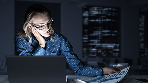 A person monitoring e-marketing efforts through a laptop and graphs