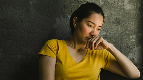 A dejected person looking down while seated in a dark room