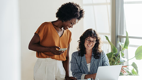 Happy professional women collaborating with enthusiasm in a modern office setting