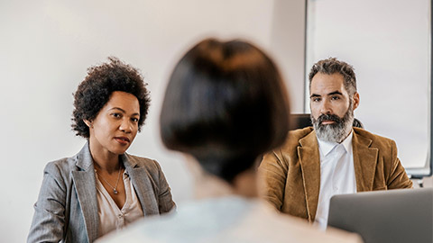 a group of three people having a discussion in an office