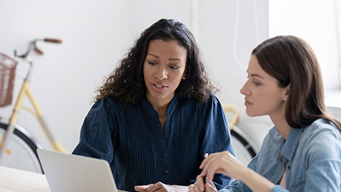 Confident young african american businesswoman tells new project to female mentor in coworking boardroom at meeting.